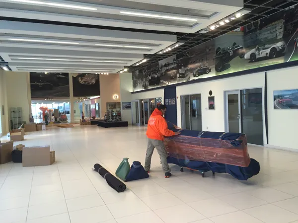 Mover in an orange shirt wrapping furniture in a large showroom