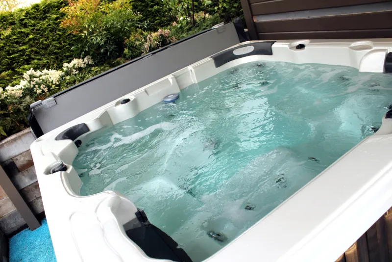 Hot tub set into a backyard deck surrounded by shrubs