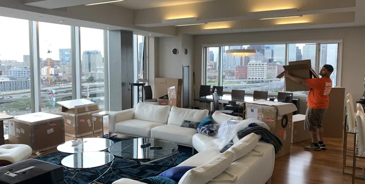 Mover unpacking boxes in a high-rise living room with city views
