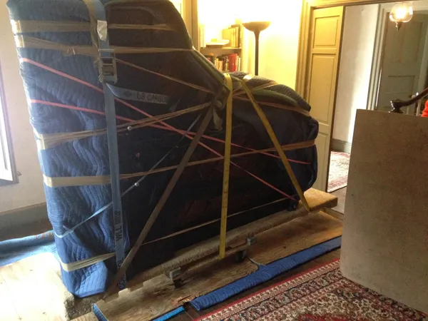 Meade mover wrapping a large piece in moving blankets in a bright showroom hall