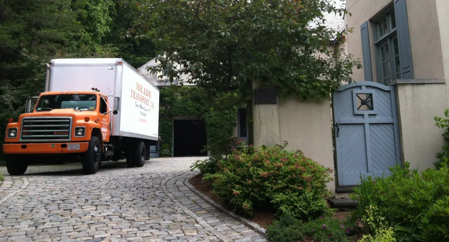 Meade truck on a cobblestone driveway beside a garden gate